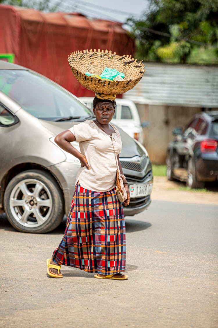 A Woman Carrying A Basket On Head Walking On Road
