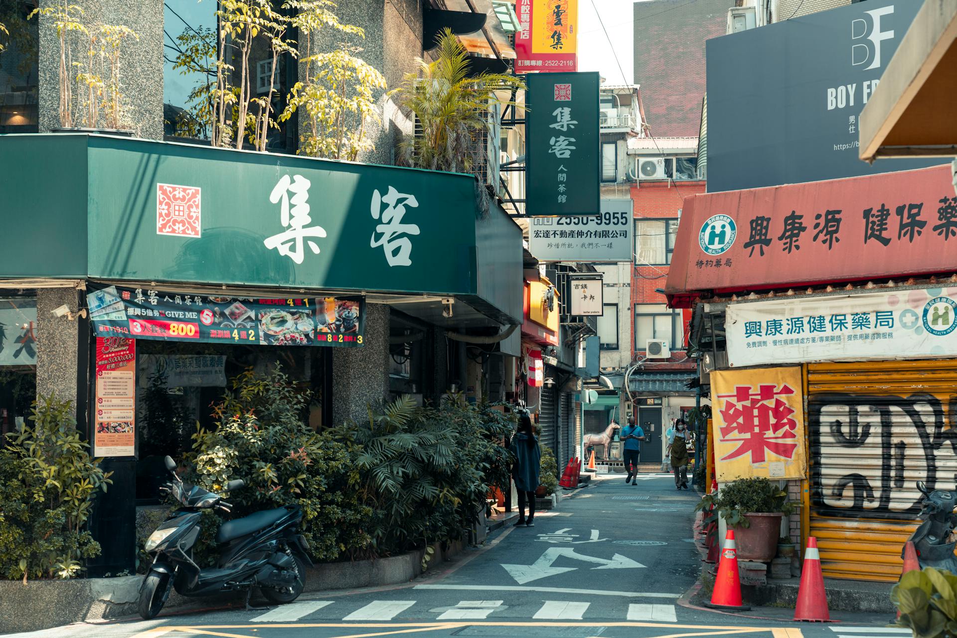 A bustling alley in Taiwan lined with shops, showcasing vibrant urban life and signage.