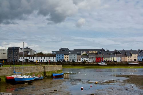 Free Charming row of colorful houses along waterside in Galway, Ireland, under a cloudy sky. Stock Photo