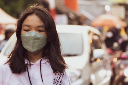 Free A teenage girl wearing a face mask in an urban setting, reflecting the pandemic era. Stock Photo