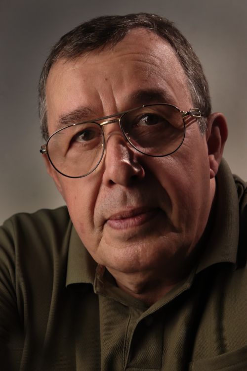Free Close-up portrait of a senior man wearing glasses and a green shirt, looking thoughtful. Stock Photo