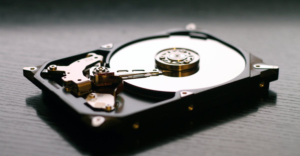An open hard drive is displayed on a wooden surface, showcasing its internal components and metallic details.