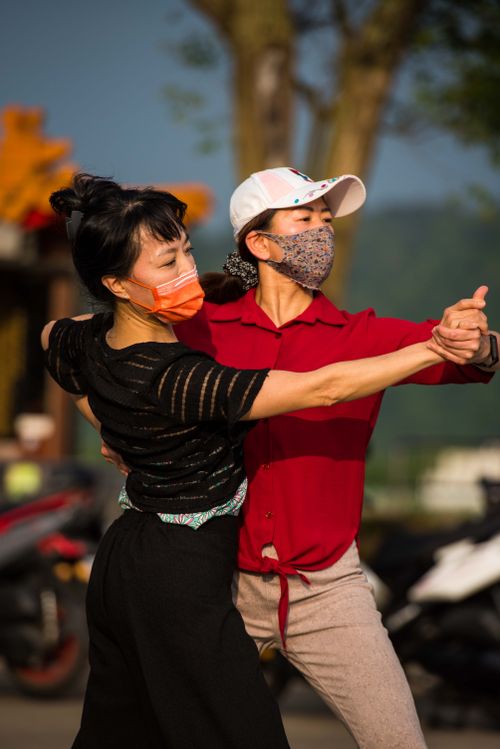 Free A couple dances gracefully outdoors wearing face masks, enjoying a sunny day. Stock Photo