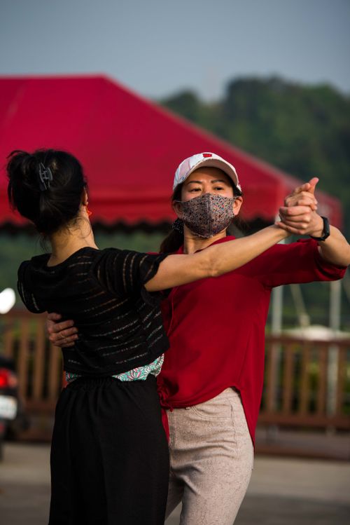 Free A couple wearing masks dancing outdoors, embracing new norms during the pandemic. Stock Photo