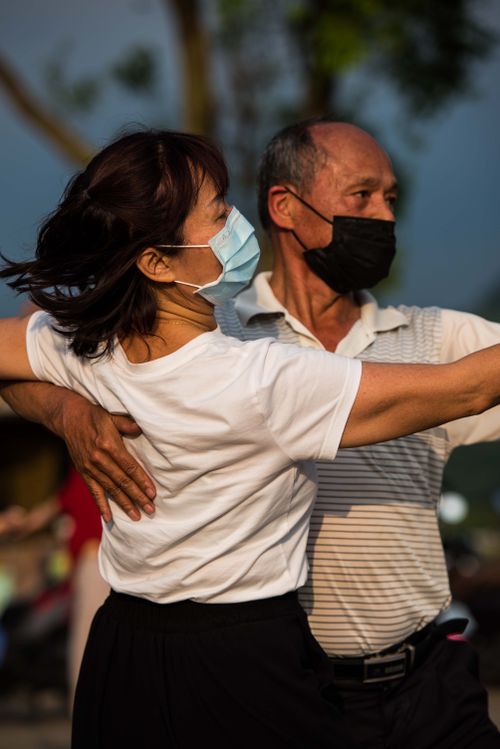 Free A couple wearing face masks dances gracefully outdoors at sunset. Stock Photo