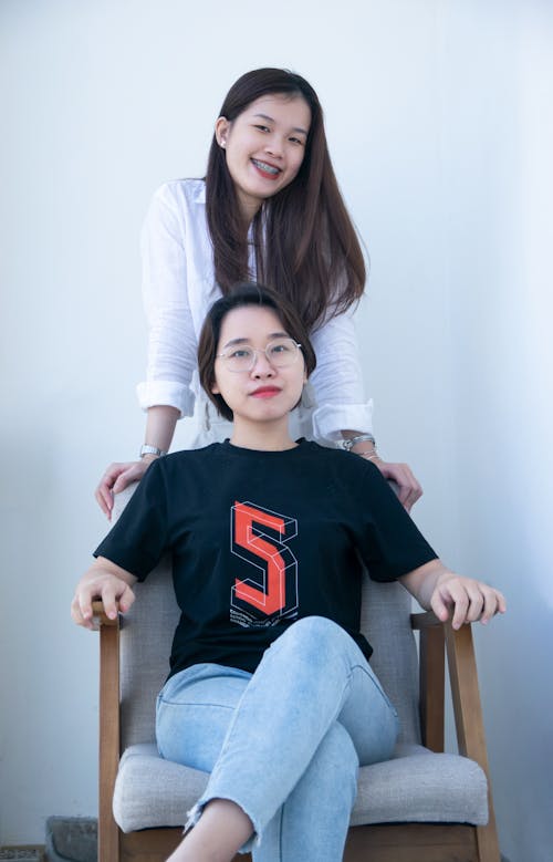 Two Brunette Women Posing with a Chair