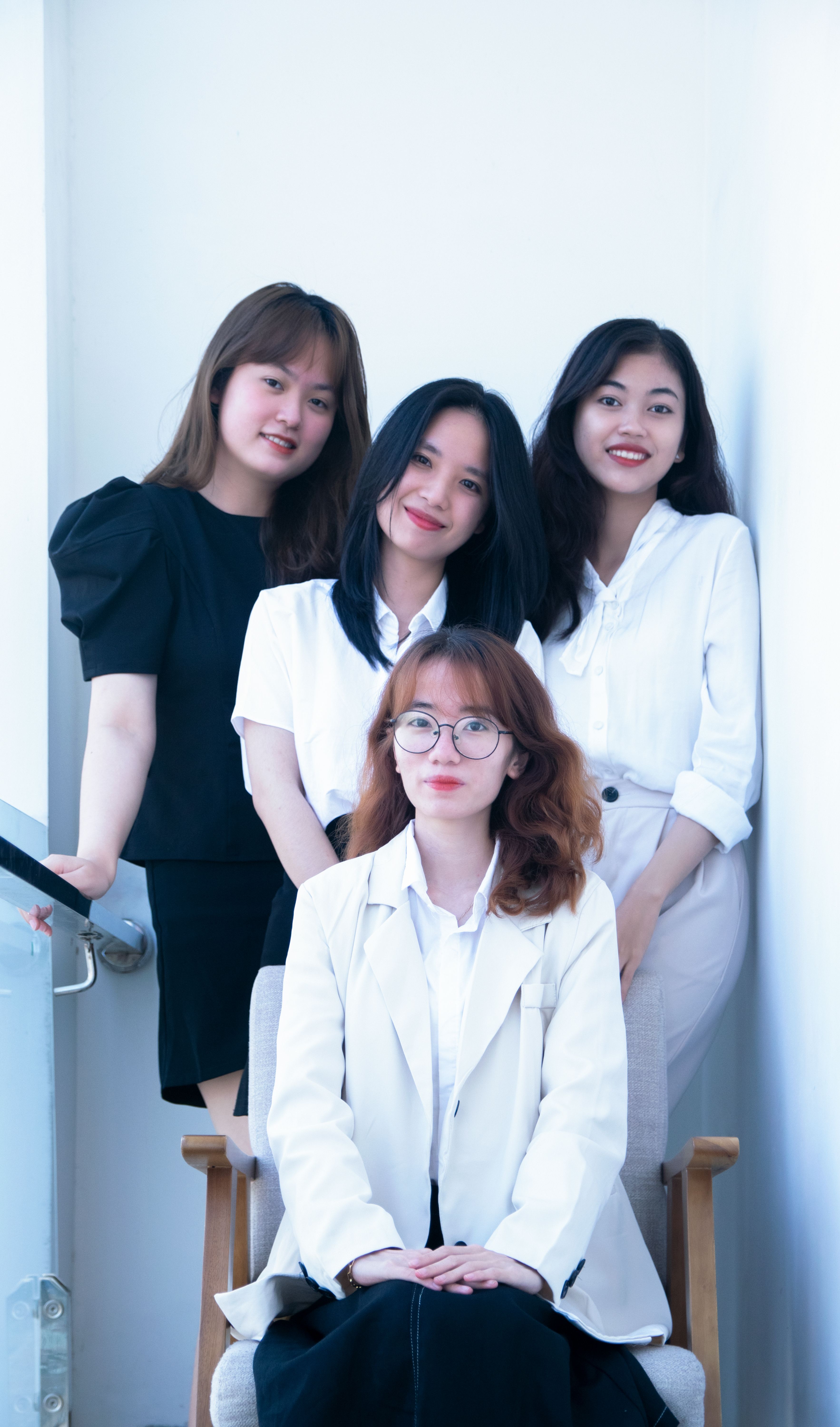 Portrait of four young women smiling and posing together in a bright indoor setting.