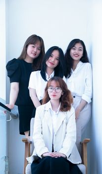 Portrait of four young women smiling and posing together in a bright indoor setting.