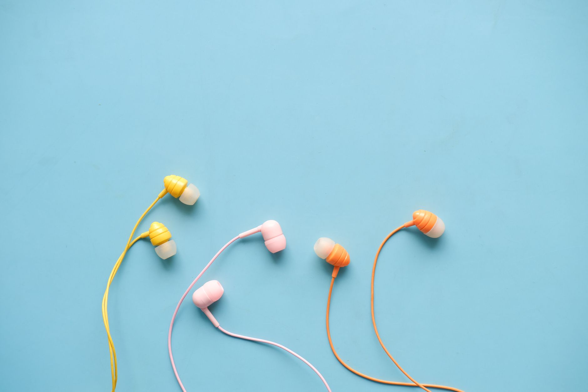 Vibrant earphones with a blue backdrop, perfect for tech visuals.