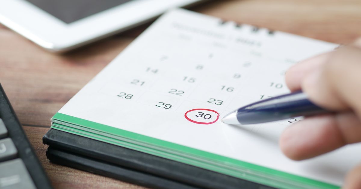 Mão marcando uma data em um calendário com caneta, simbolizando agendamento de manutenção preventiva