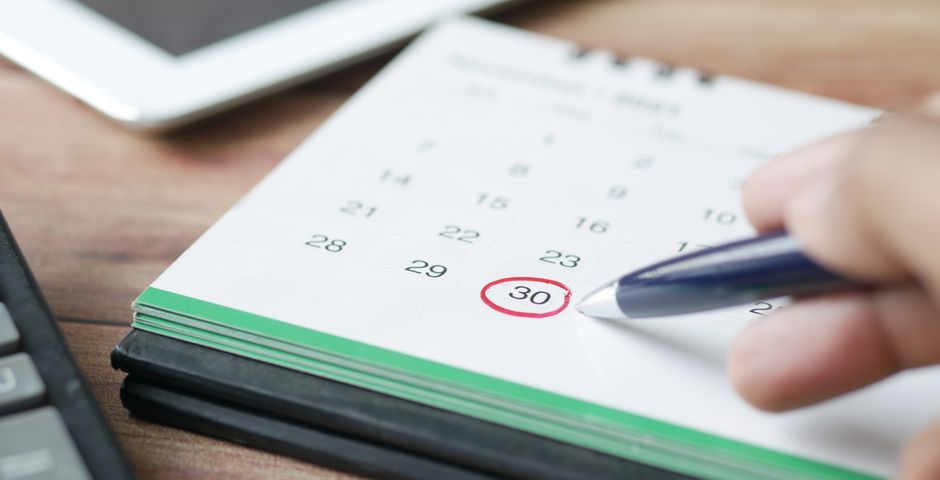 A hand marking a date on a calendar — planning a yearly pest control schedule for a Malaysian home
