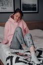 Woman in Pink Hoodie and Gray Pants Lying on Bed
