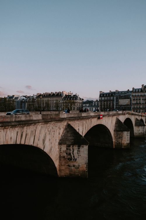 Free A picturesque Parisian bridge with historic buildings under a blue sky at dusk. Stock Photo