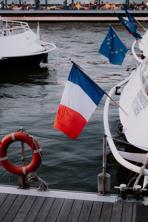 Free Docked boats displaying French and EU flags at a marina, creating a serene outdoor scene. Stock Photo