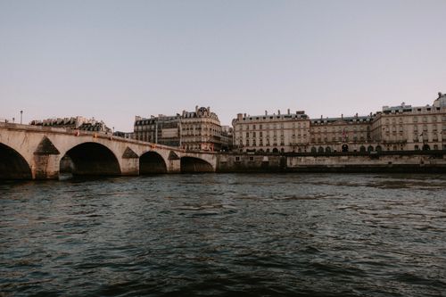 Free Beautiful early evening view of a historic stone bridge crossing the Seine River in Paris. Stock Photo