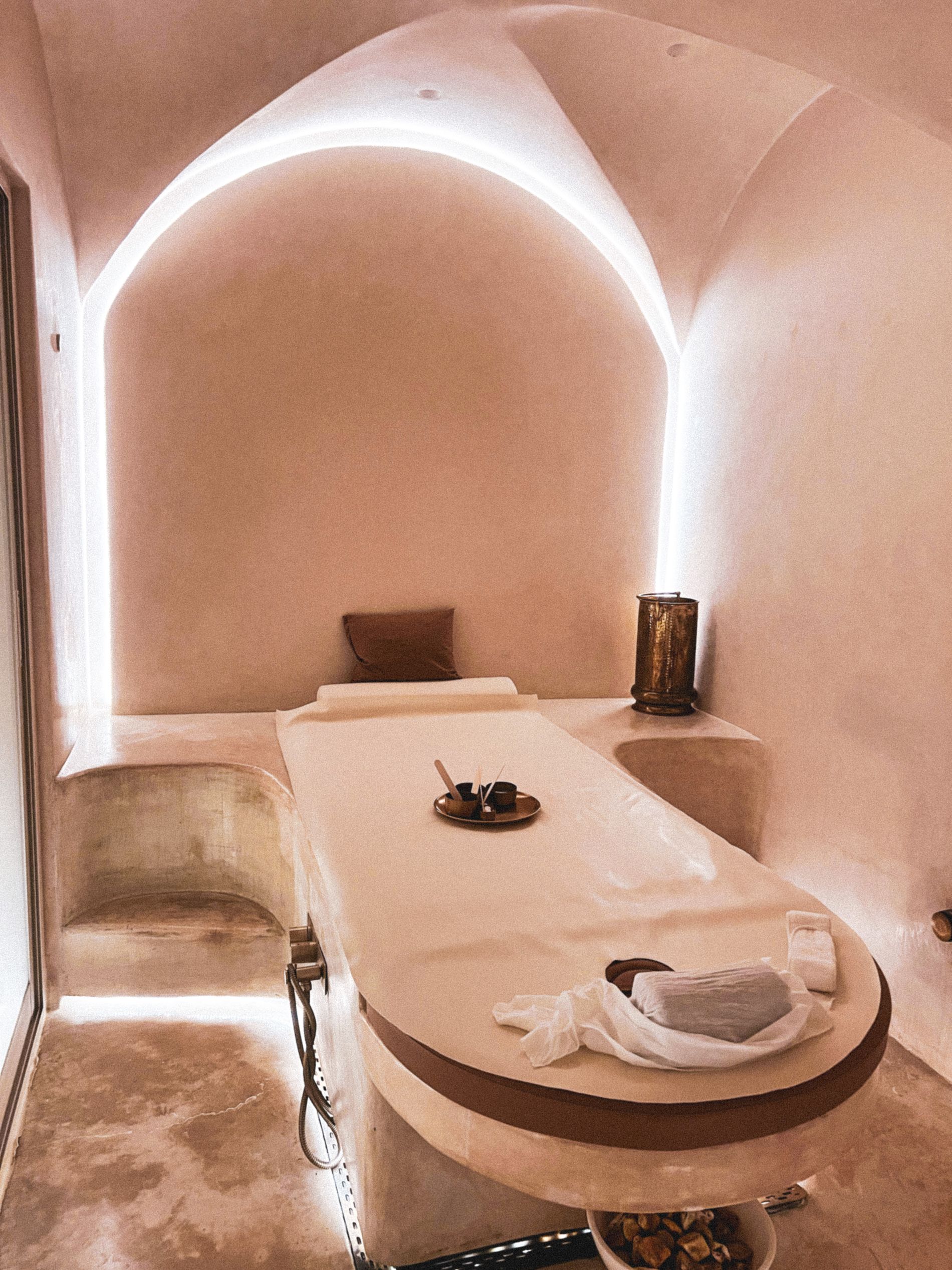 A dimly lit spa suite with candles, warm wood and soft linen