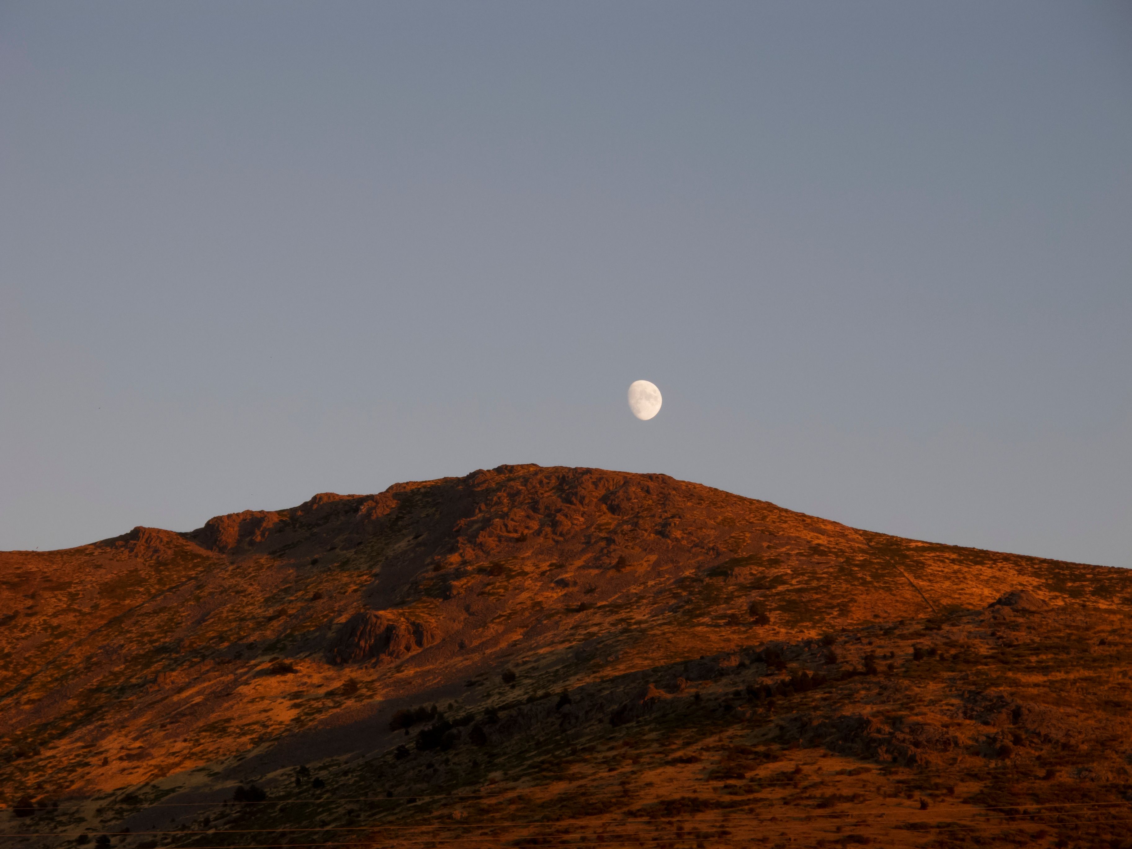 Scenic view of a mountain with the moon rising in Otero de Herreros, Spain at dusk.