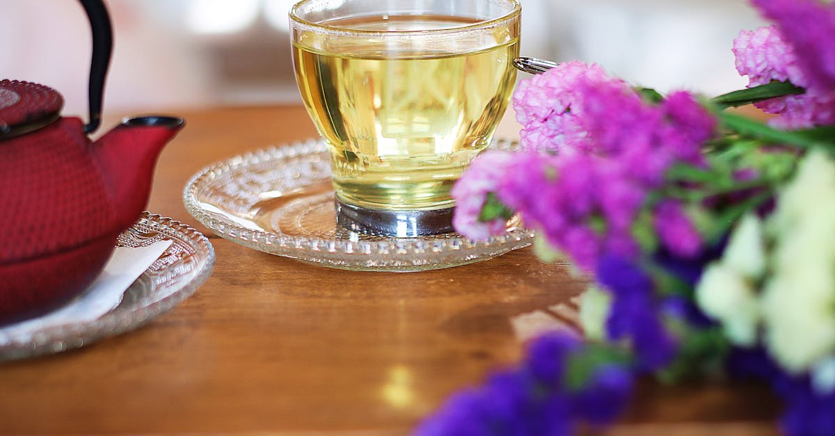 A warm cup of tea with a teapot and colorful flowers on a wooden table, capturing a serene moment.