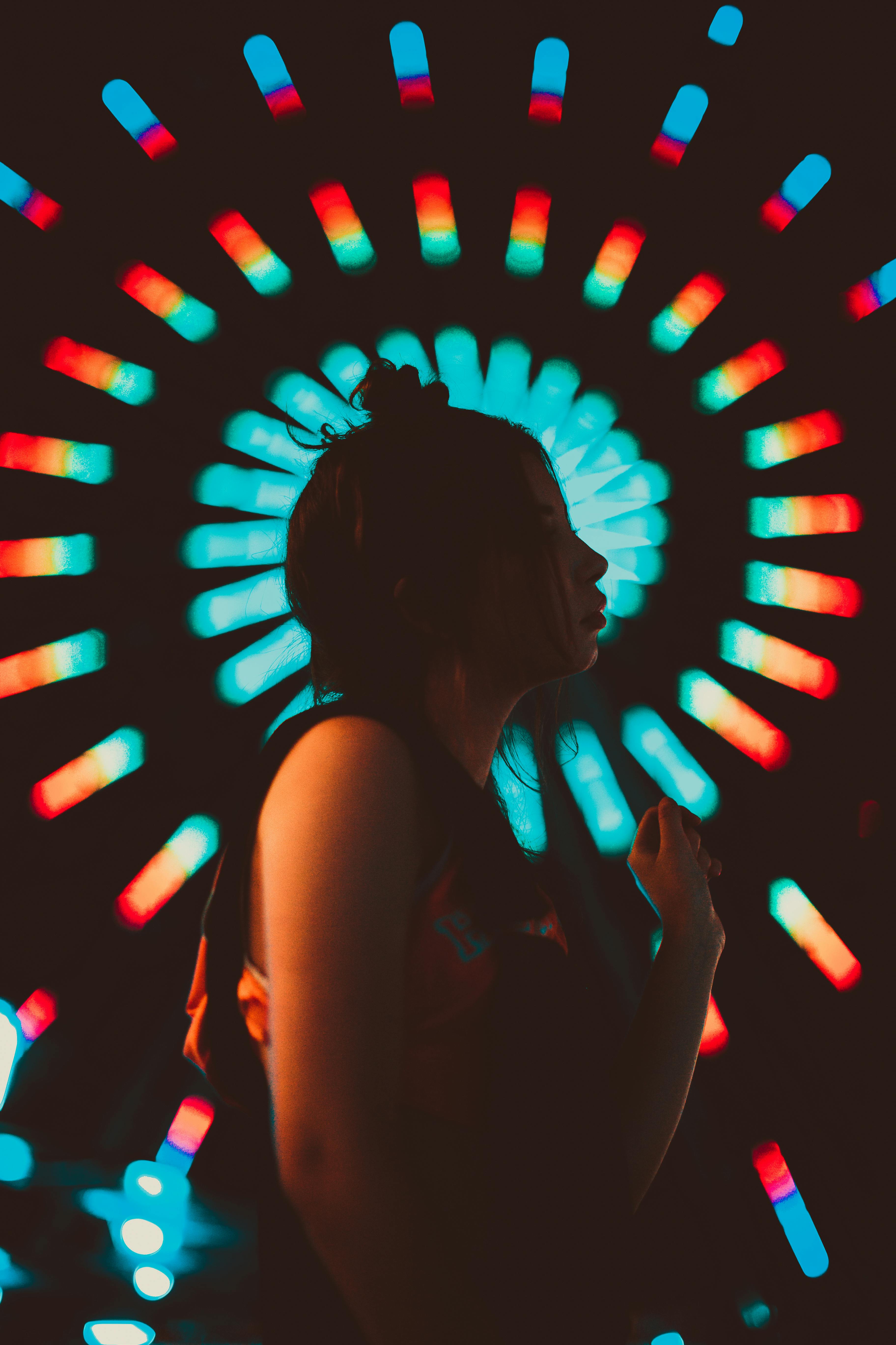 以彩色摩天轮灯光为背景的女子剪影，营造出迷人的夜色