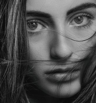 Close-up black and white portrait of a woman highlighting eyes and hair.