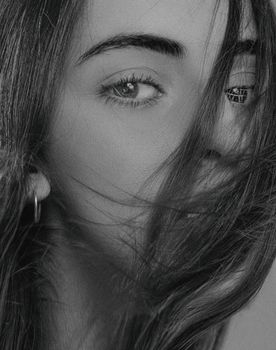 Monochrome portrait of a woman with hair covering her face in a stylish pose.