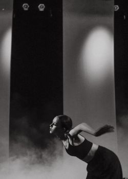 Dramatic black and white shot of a dancer in motion on a smoky stage.