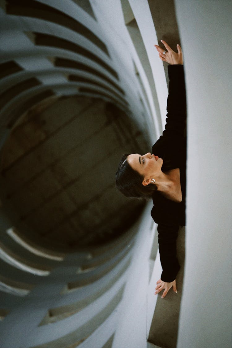 A Woman Leaning Forward From The Building Ledge