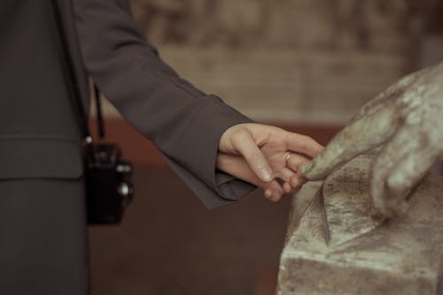 Free Hand of Woman Touching Fingers of a Sculpture Stock Photo