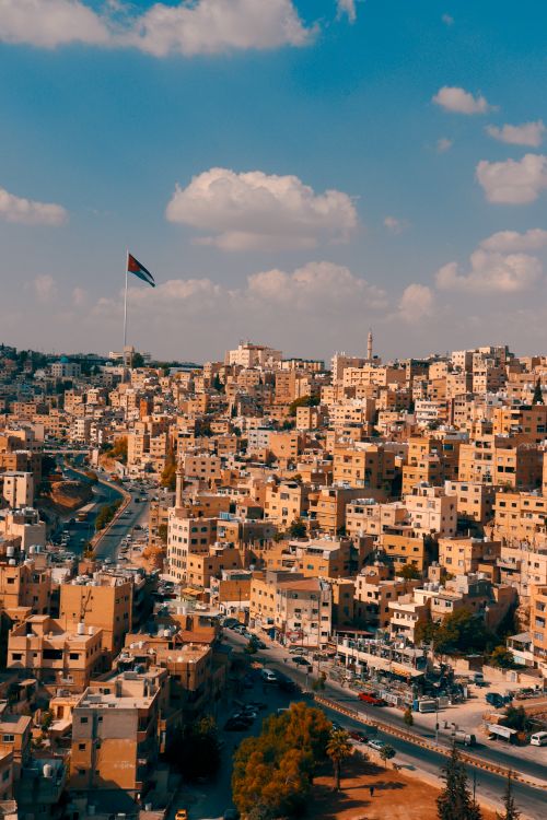 Free A breathtaking aerial view of Amman, Jordan, showcasing urban architecture and the national flag. Stock Photo