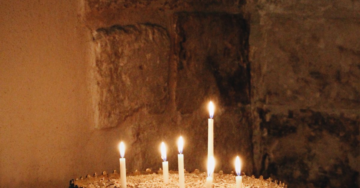 Several candles burning in a quiet stone interior