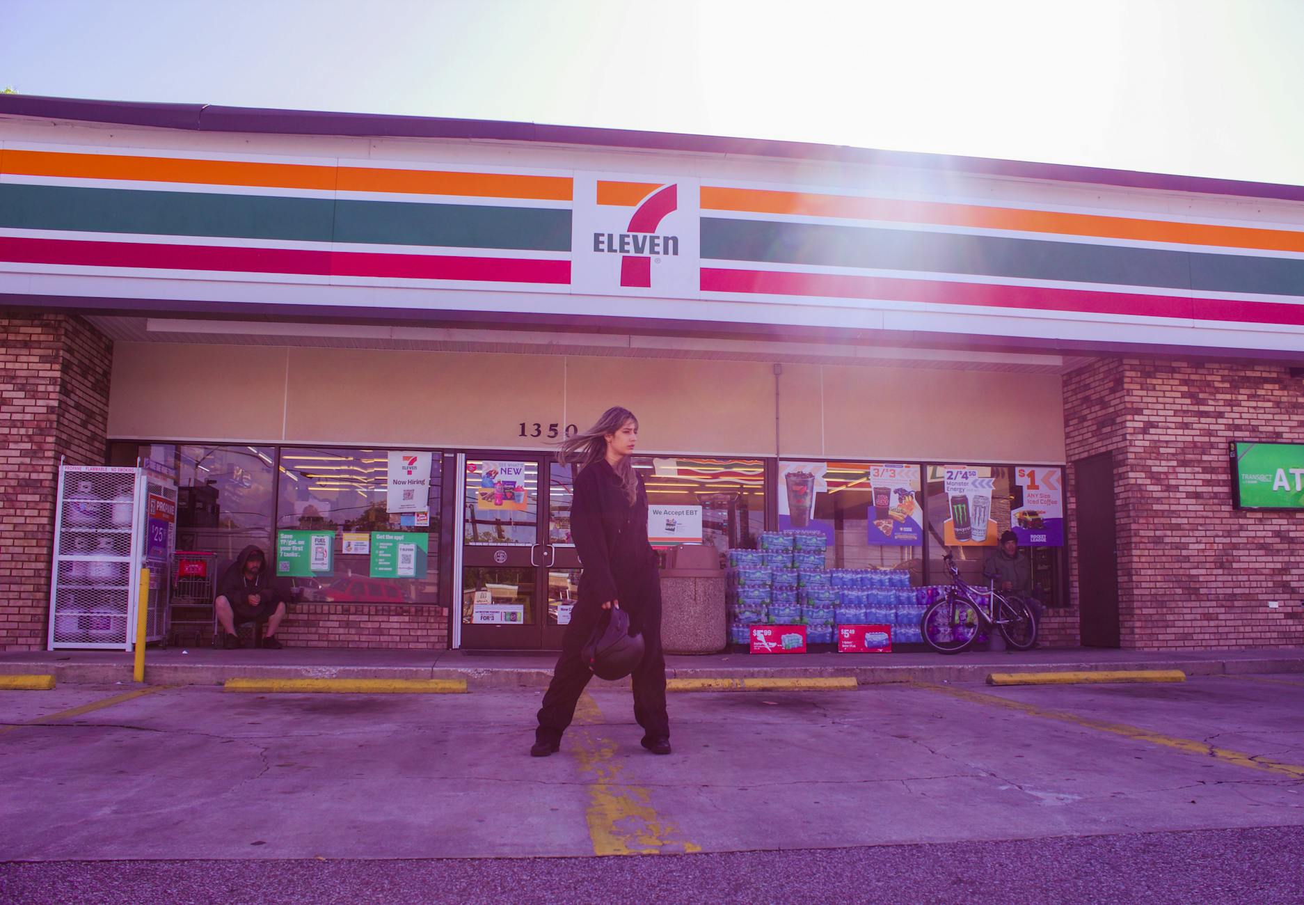 Fashionable woman posing in front of a 7-Eleven store at daytime, urban style.