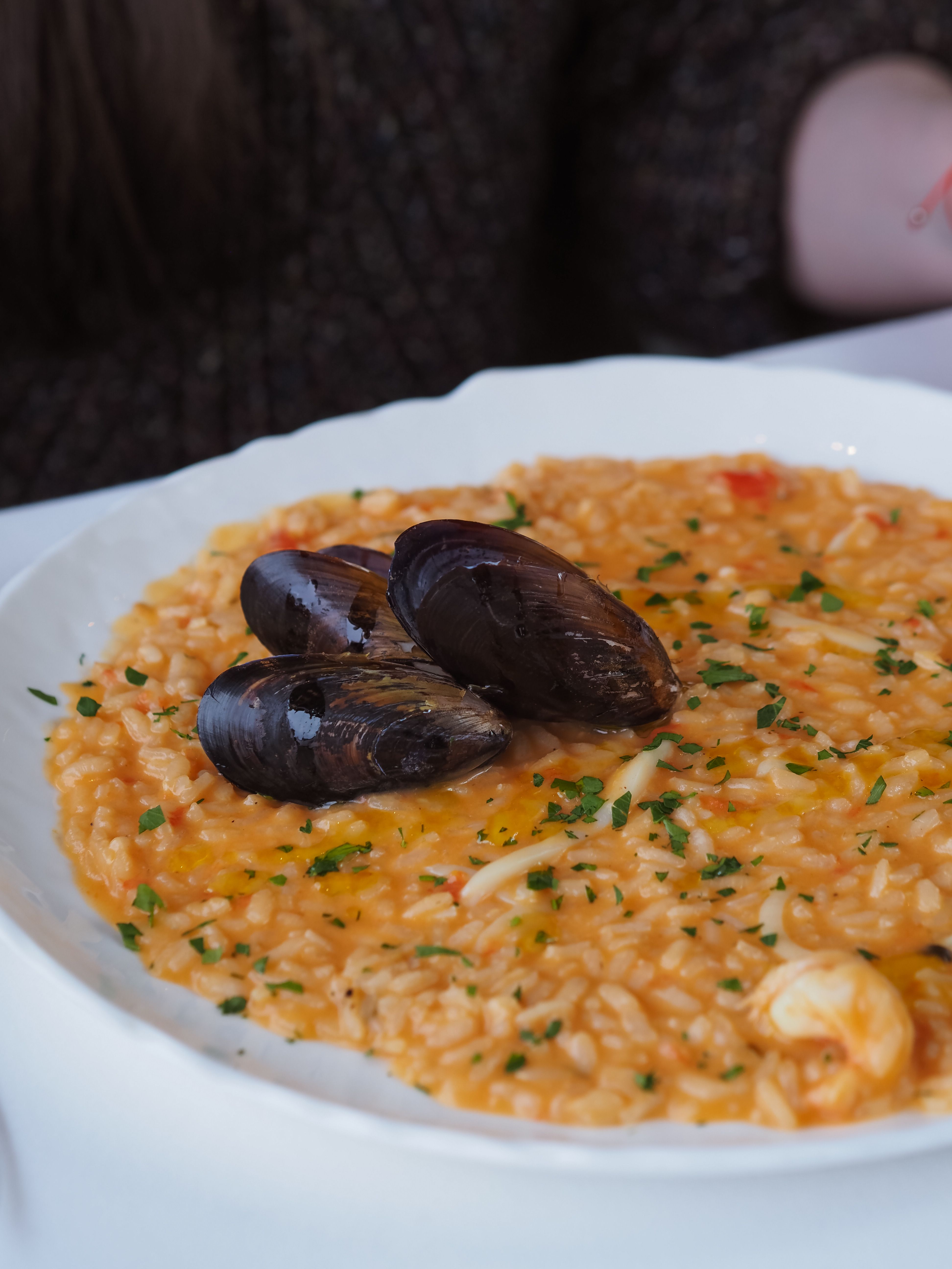 Savor a rich seafood risotto topped with fresh mussels, artfully plated and garnished.