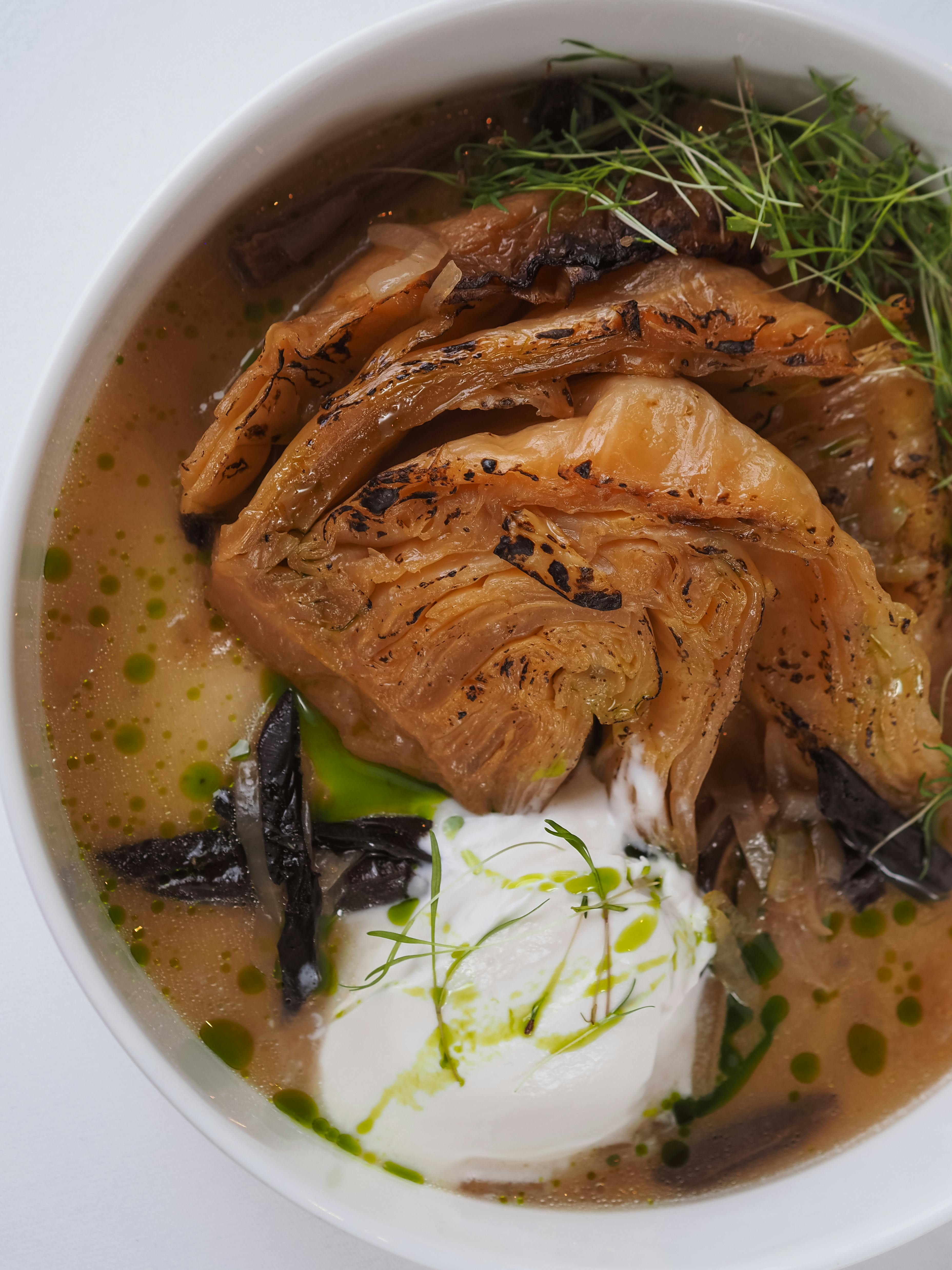Close-up of a gourmet cabbage top soup garnished with cream and herbs, showcasing rich flavors.