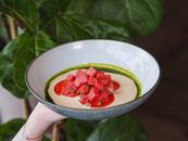 Person Holding White Ceramic Bowl With Sliced Tomato and Green Leaf