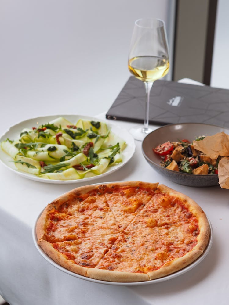 Pizza Margherita Salads And Glass Of White Wine In Restaurant