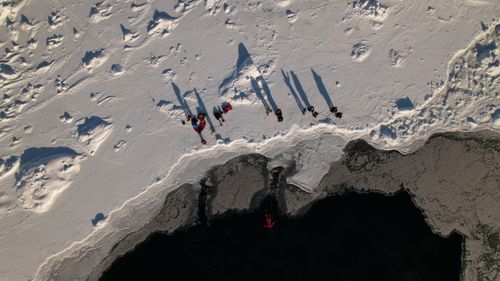 Free Drone shot capturing people exploring the icy landscape near an arctic coast. Stock Photo