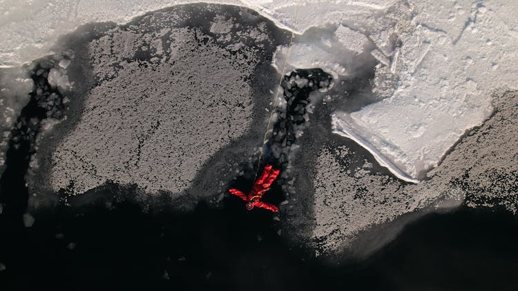 A Man In Red Jacket Swimming On Frozen Lake