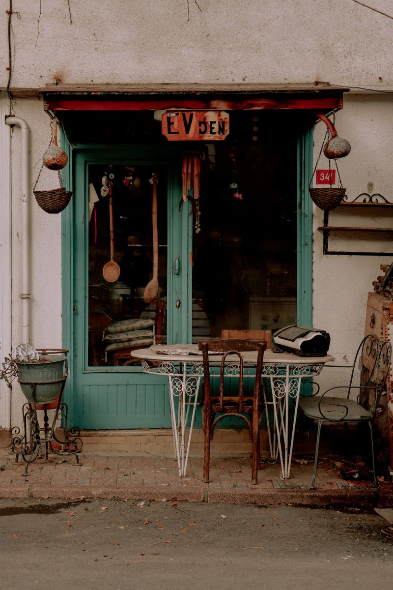 A rustic shop entrance with a painted teal door and eclectic goods displayed outside