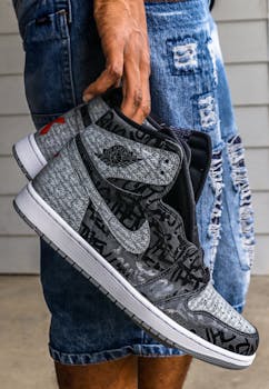 Close-up of trendy black and grey Nike sneakers being held, showcasing modern fashion style.
