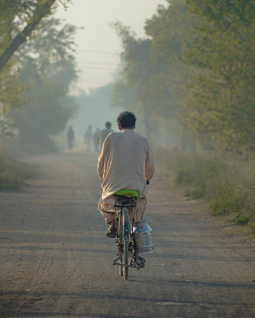 Backview of Man in Riding Bicycle in an Unpaved Road