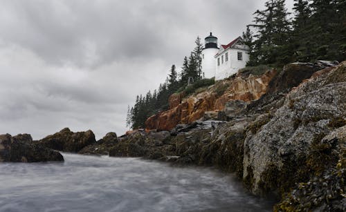 White and Red Concrete Lighthouse Near the Ocean