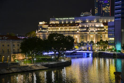 The Fullerton Hotel illuminated at night with water reflections in Singapore.