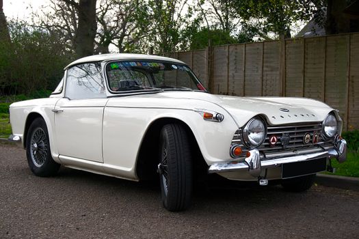 Elegant white Triumph sports car showcased outdoors, embodying vintage automotive style.
