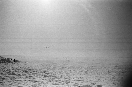 Monochrome landscape of a snowy beach with a tranquil sky, ideal for winter art.