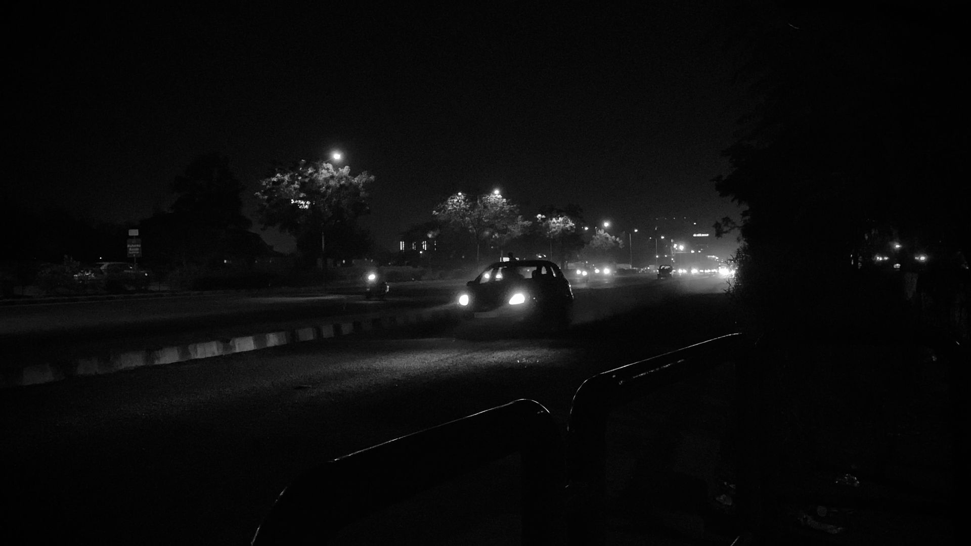 A nighttime black and white street scene with cars and streetlights, offering a moody urban vibe.