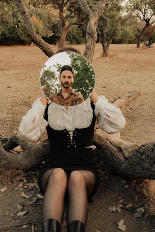 Woman Holding a Mirror on Her Face with a Man's Reflection