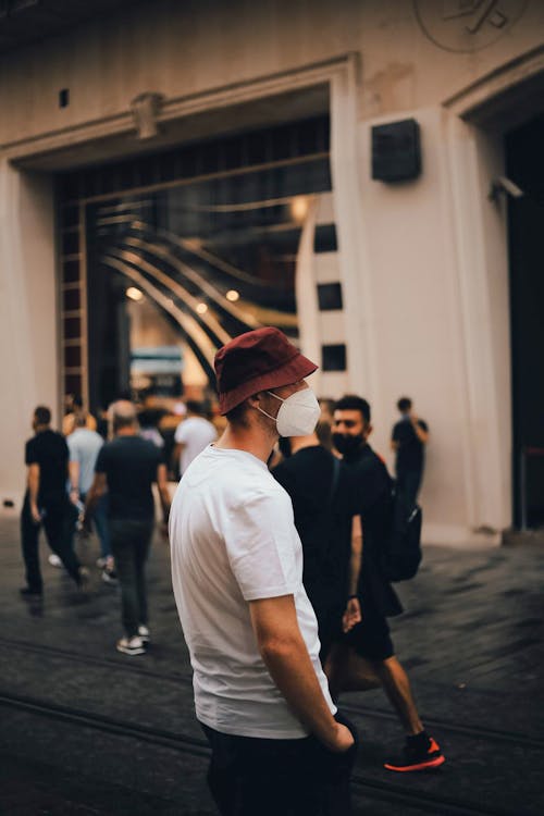 Man in White T-shirt and Red Hat Standing Near Building