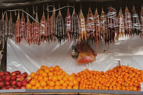 Dried Sausages Hanging on Fresh Fruits on a Fruit Stand