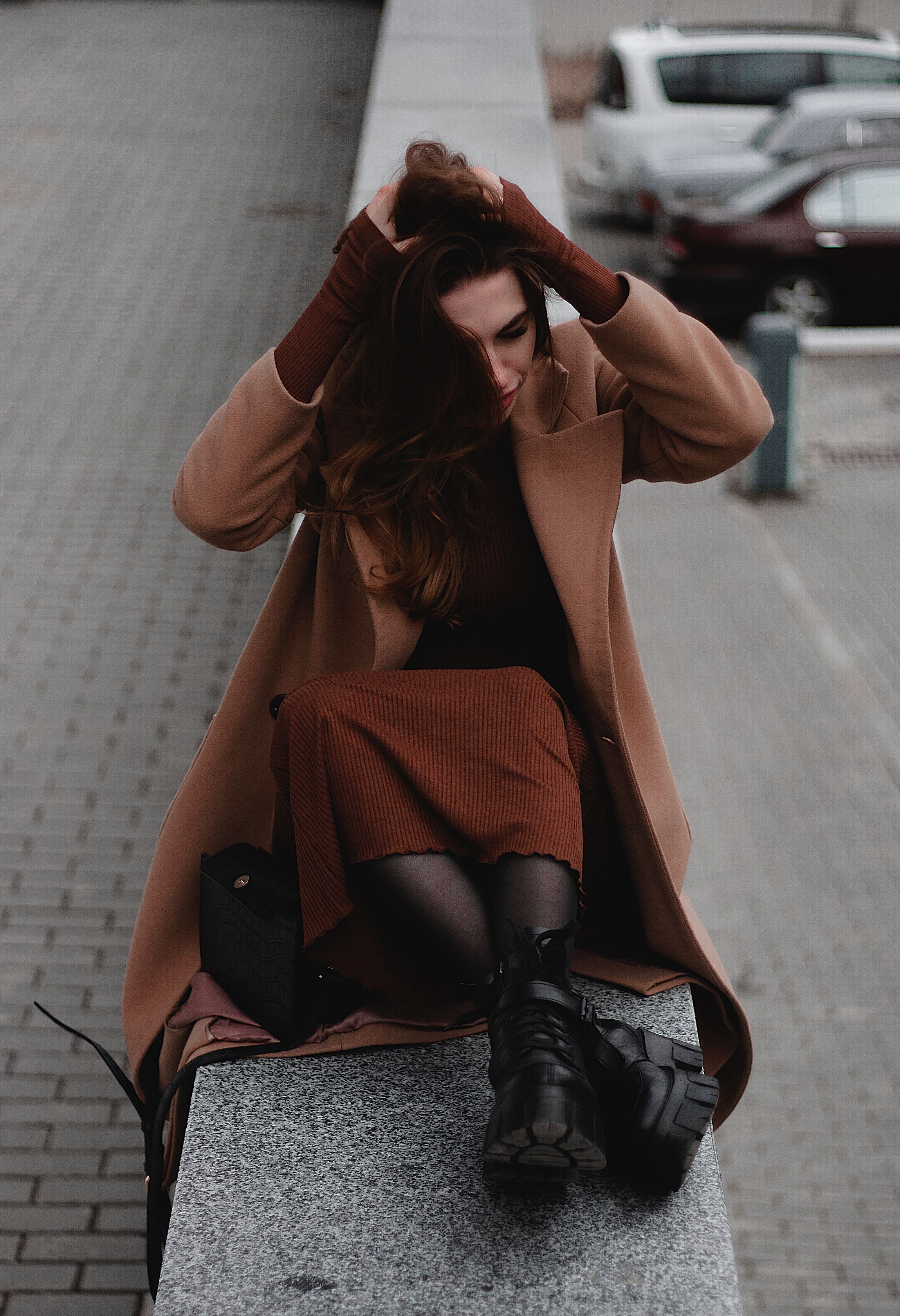 A Woman in Brown Trench Coat Sitting on the Ledge · Free Stock Photo