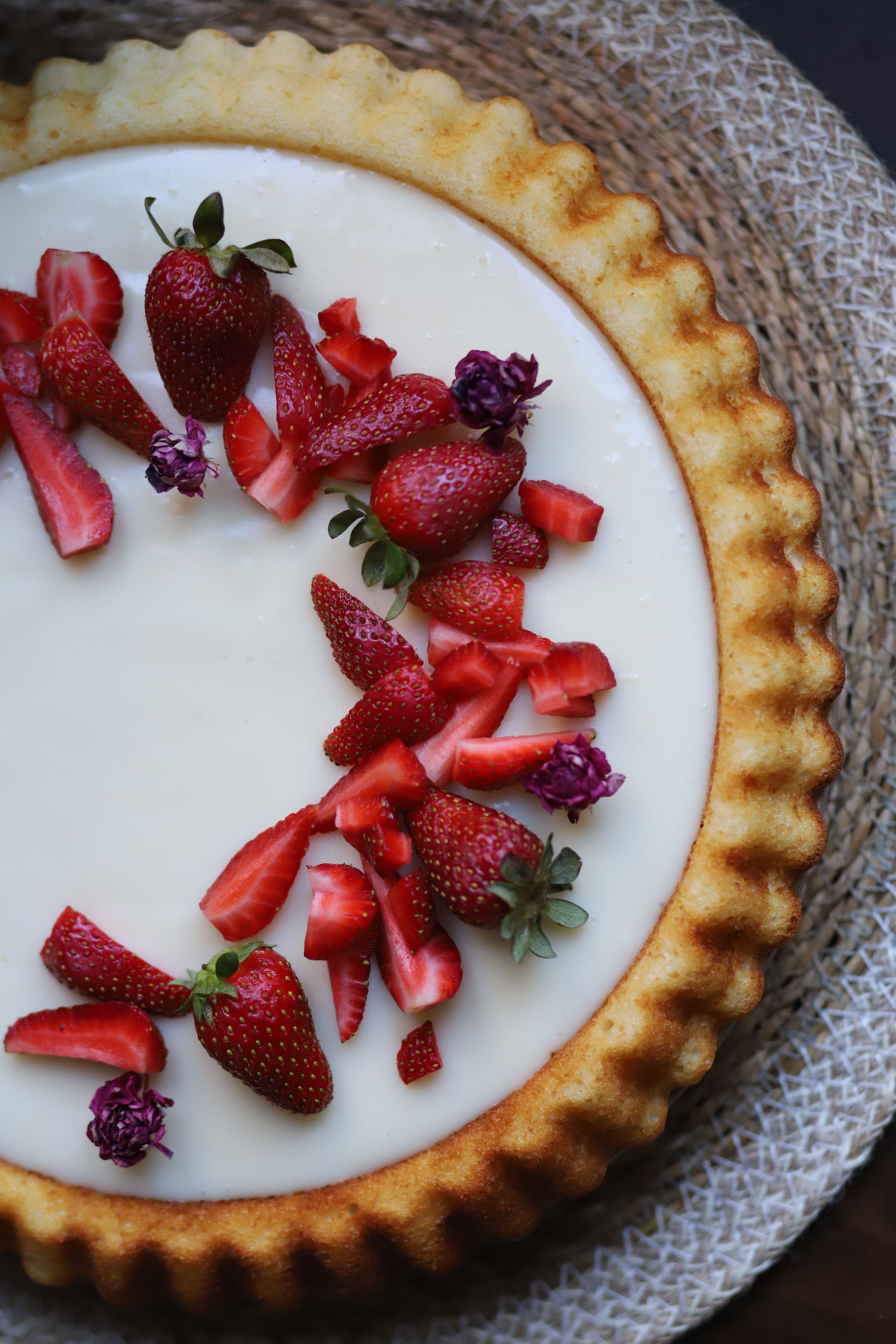 Tasty cheesecake adorned with fresh strawberries on a woven placemat, perfect for dessert lovers.